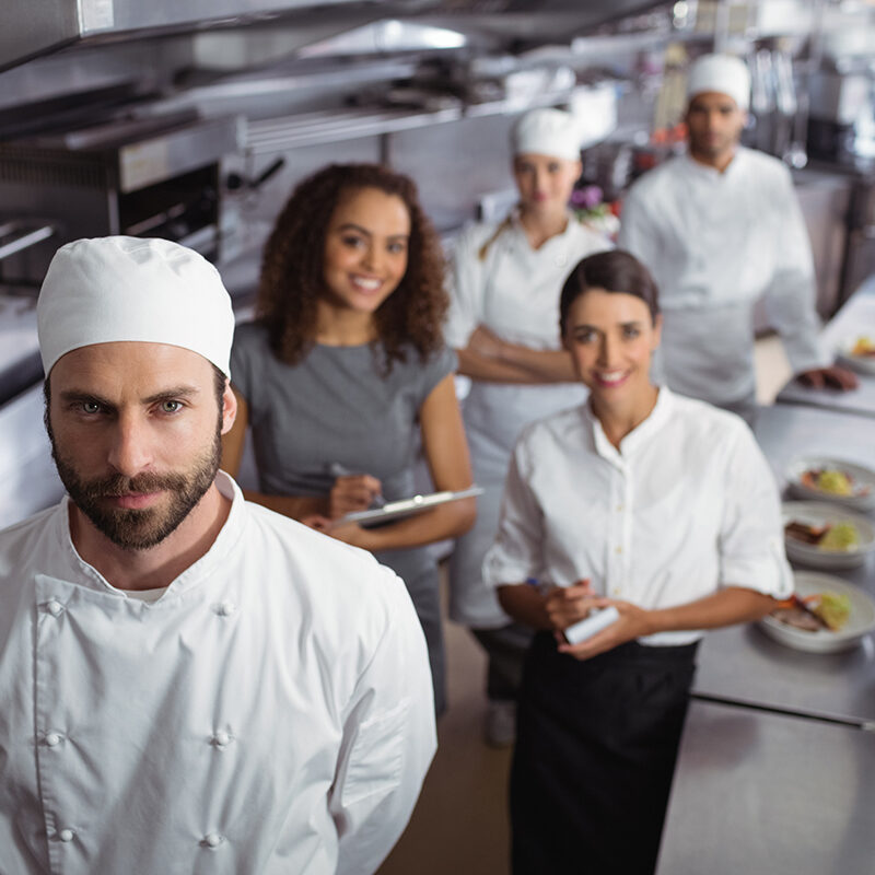Portrait of restaurant manager with his kitchen staff in the commercial kitchen
